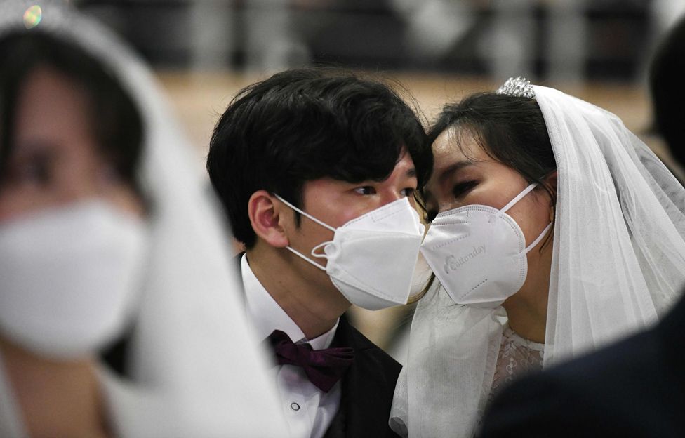 A masked couple share a moment during a mass wedding ceremony organised by the Unification Church in Gapyeong